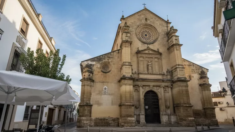 Templo de piedra visto desde calle estrecha con terrazas en primer plano.