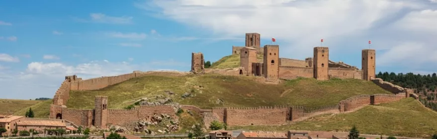 Castillo amurallado sobre colina y tejados del pueblo.