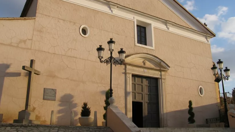 Fachada sencilla con puerta central, escaleras y farolas.