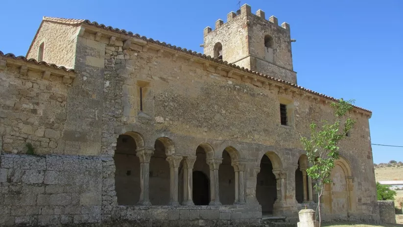 Fachada con galería porticada y torre almenada.