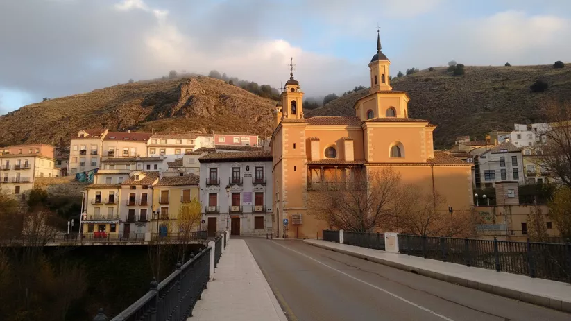 Iglesia junto a puente y casas al atardecer