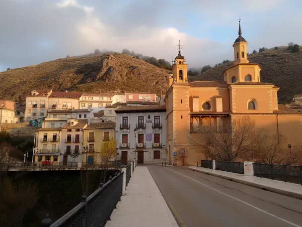 Iglesia junto a puente y casas al atardecer