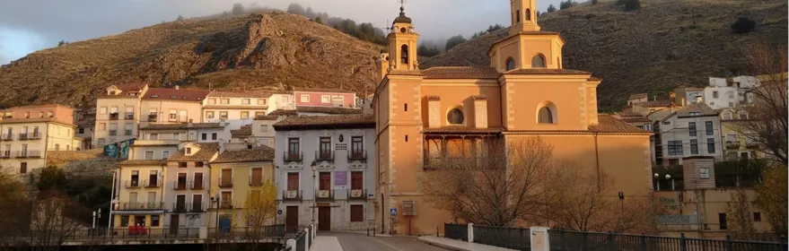 Iglesia junto a puente y casas al atardecer