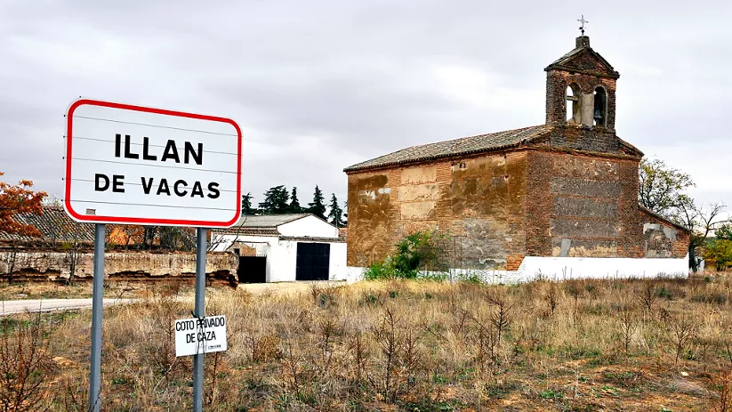 Cartel de entrada junto a una iglesia de ladrillo