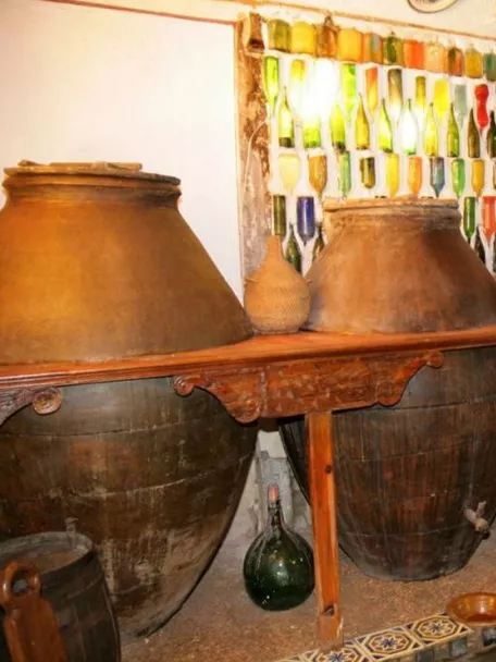Tinajas tradicionales alineadas en sala con botellas de vidrio decorativas