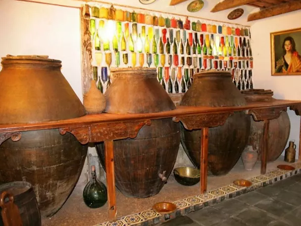 Tinajas tradicionales alineadas en sala con botellas de vidrio decorativas