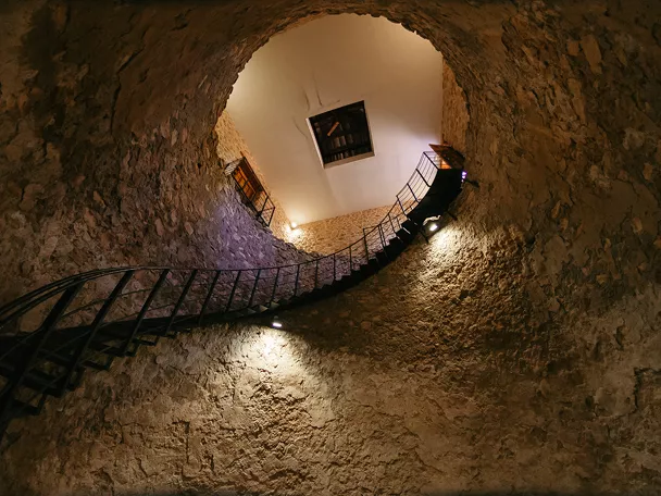 Escalera circular iluminada en interior de pozo excavado en piedra