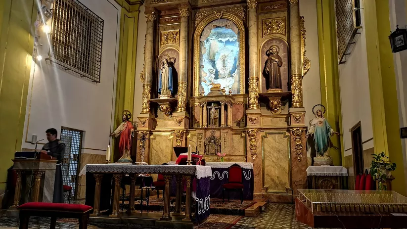 Altar barroco dorado con imágenes y flores.