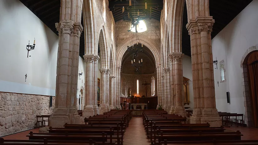 Nave central con arcos y columnas de piedra.