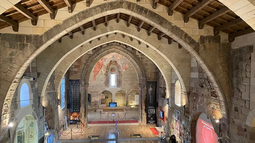 Nave de piedra con arcos apuntados y techo de madera.