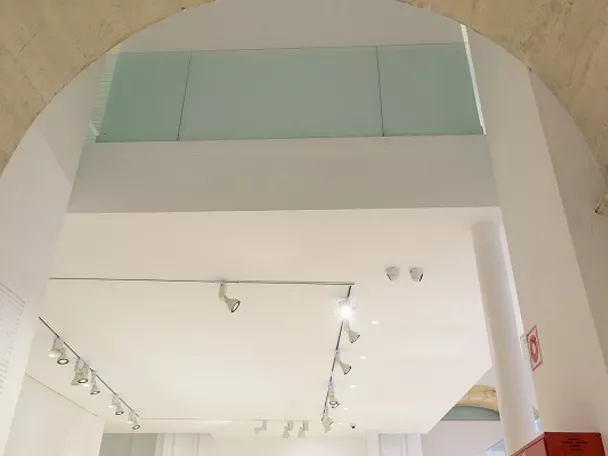 Sala expositiva con arco de piedra y vitrinas iluminadas.