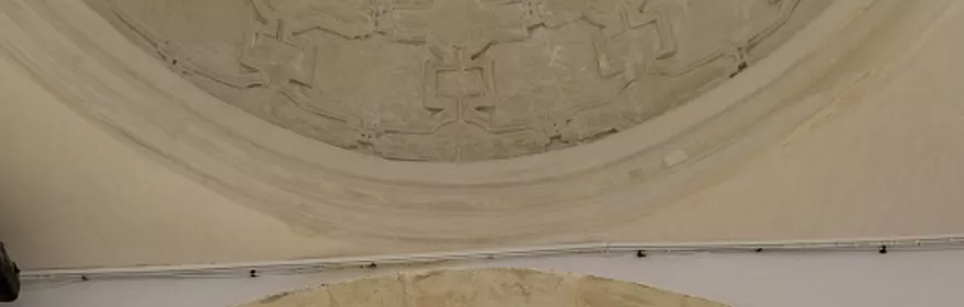 Sala expositiva con arco de piedra y vitrinas iluminadas.