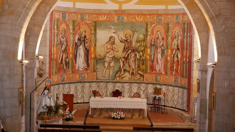 Altar con mural bíblico y arco de piedra.