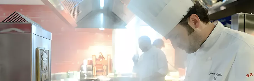 Cocinero trabajando entre vapor en una cocina profesional