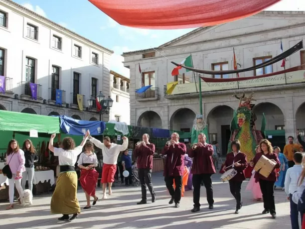 Actuación musical y baile en una plaza decorada con puestos y banderines.