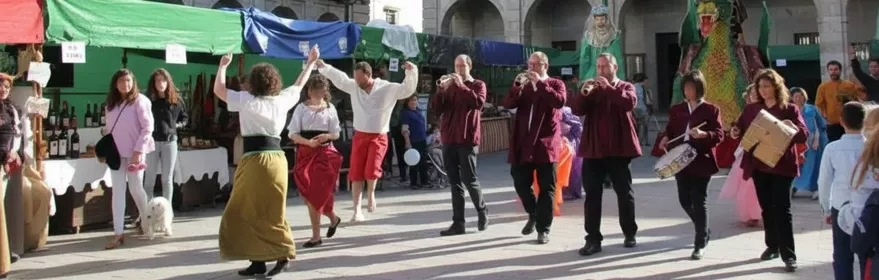 Actuación musical y baile en una plaza decorada con puestos y banderines.