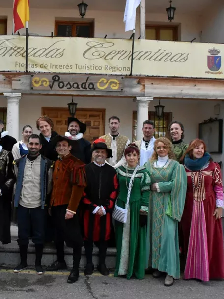 Grupo de personas con vestimenta histórica posando delante de un edificio con balcones.