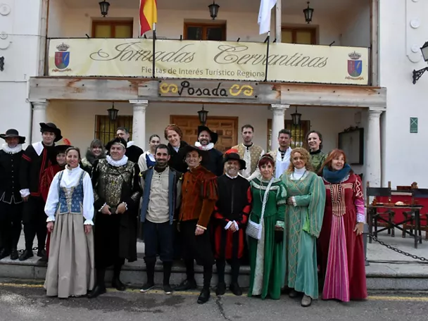Grupo de personas con vestimenta histórica posando delante de un edificio con balcones.