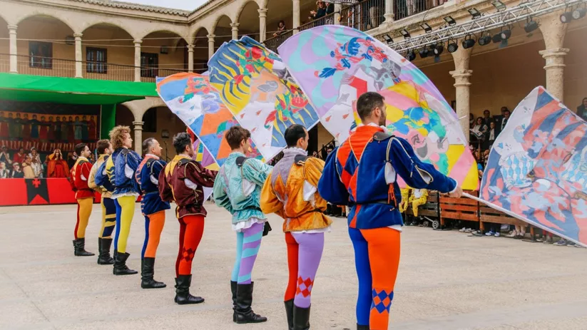 Abanderados con trajes de colores en un patio porticado