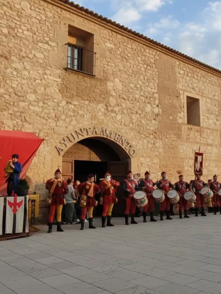 Tamborileros con trajes medievales frente a una fachada de piedra