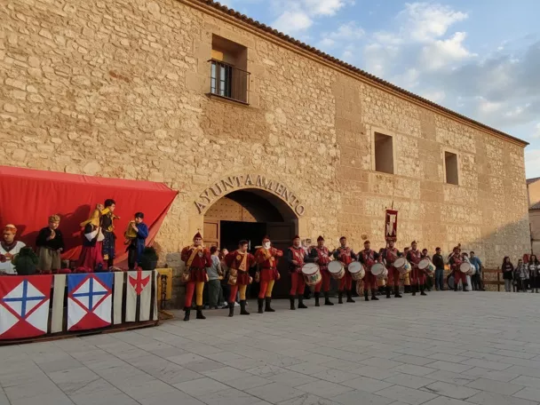 Tamborileros con trajes medievales frente a una fachada de piedra