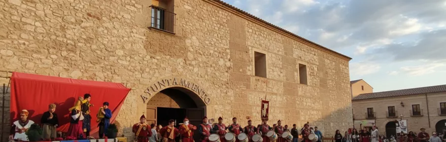Tamborileros con trajes medievales frente a una fachada de piedra