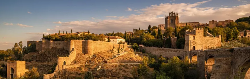 Vista panorámica de murallas, puente y río al atardecer.