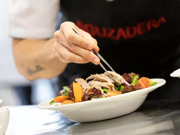 Chef emplatando ensalada fresca con pinzas