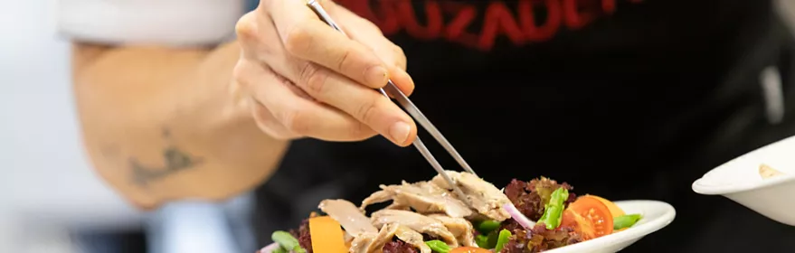 Chef emplatando ensalada fresca con pinzas