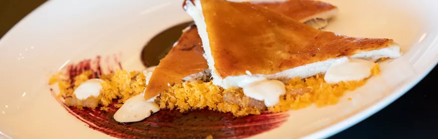 Plato de hojaldre dorado con crema y salsa