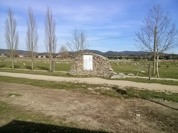 Monumento de piedra en pradera con ovejas al fondo