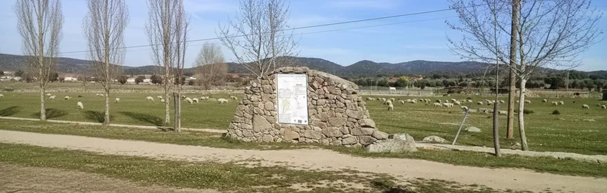 Monumento de piedra en pradera con ovejas al fondo