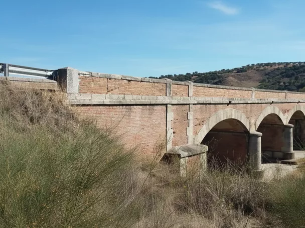 Puente de ladrillo con varios arcos sobre un arroyo