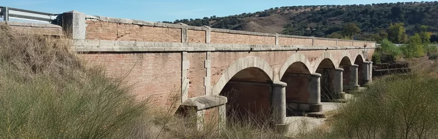 Puente de ladrillo con varios arcos sobre un arroyo