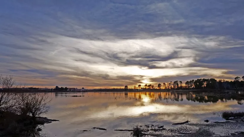 Atardecer reflejado en aguas tranquilas de una laguna