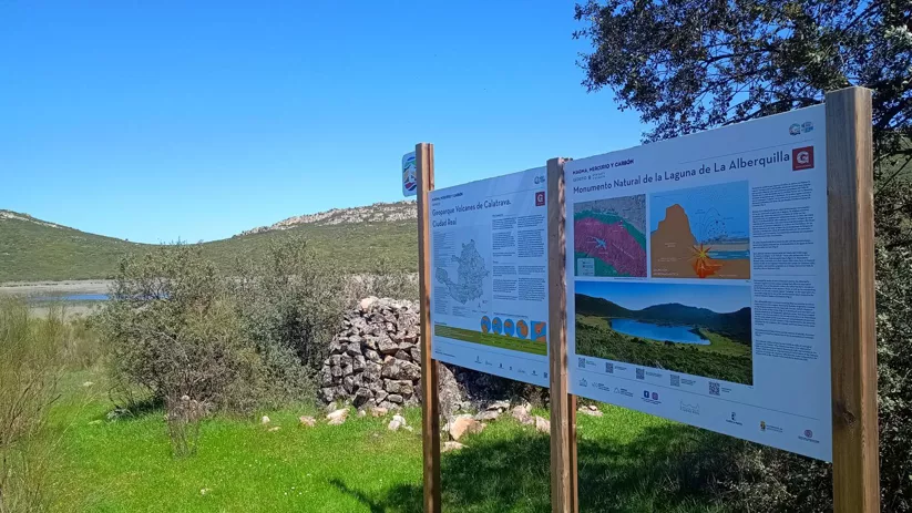 Panel informativo en sendero natural junto a paisaje verde