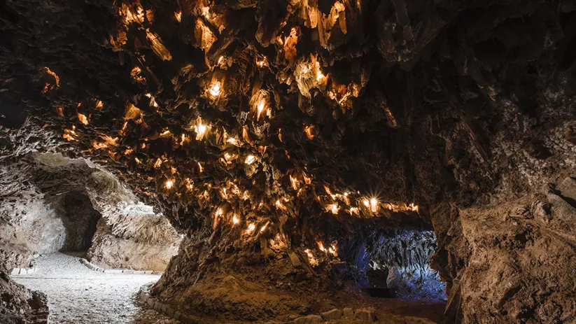 Interior de cueva iluminada con formaciones cristalinas