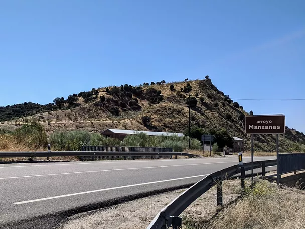 Carretera junto a ladera seca con señal marrón