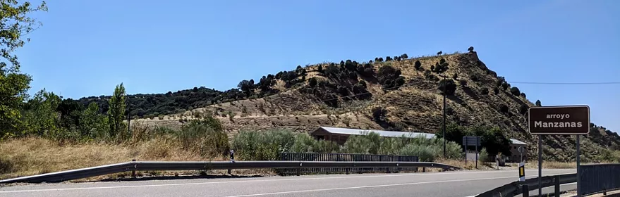 Carretera junto a ladera seca con señal marrón