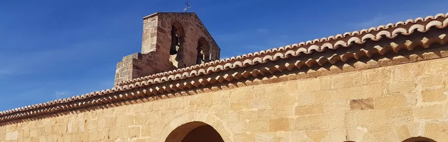 Galería porticada de piedra con arcos y espadaña.