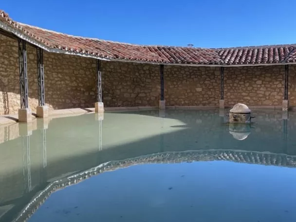Lavadero circular de piedra con cubierta de teja.