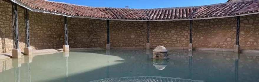 Lavadero circular de piedra con cubierta de teja.