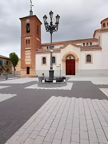 Plaza amplia con iglesia blanca, torre de ladrillo y farola central