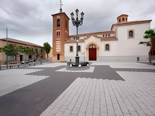 Plaza amplia con iglesia blanca, torre de ladrillo y farola central