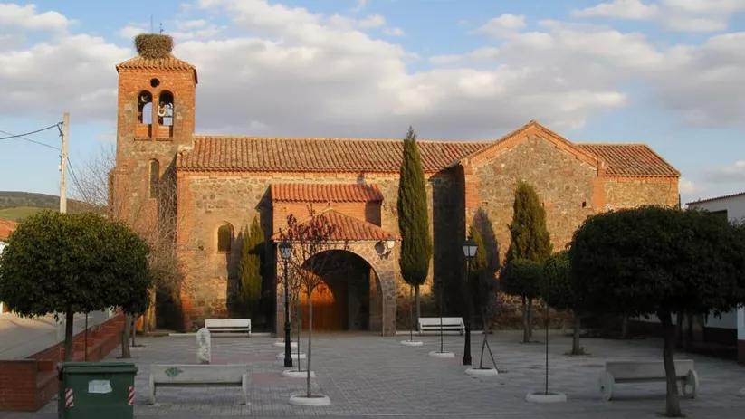 Vista lateral de la iglesia parroquial de Los Cortijos con torre campanario de ladrillo y piedra.