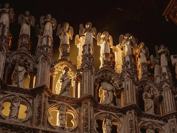 Detalle de figuras de ángeles iluminadas sobre una estructura ornamental.