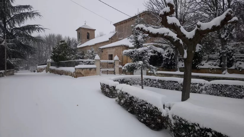 Iglesia de piedra y plaza cubierta de nieve en invierno.