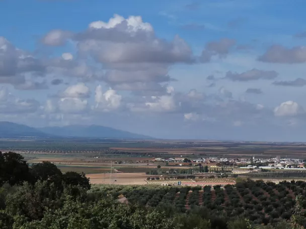 Panorámica de llanura agrícola con nubes y monte al fondo