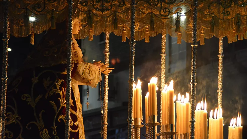 Imagen mariana bajo palio con velas encendidas.
