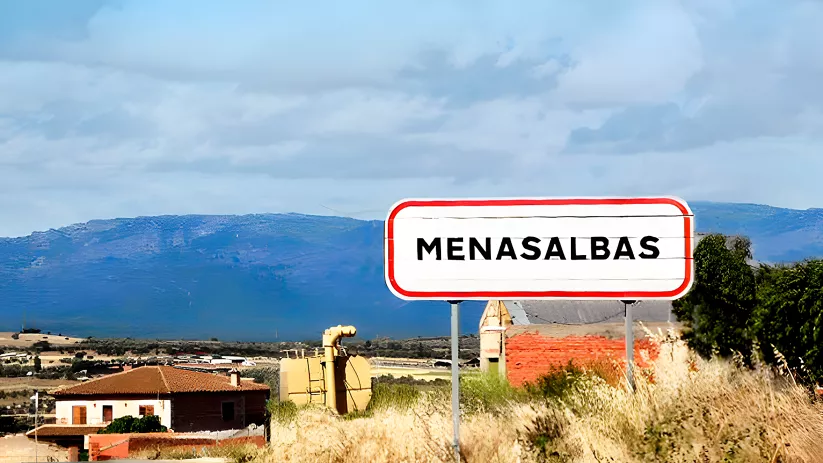 Señal de entrada al pueblo con montañas al fondo
